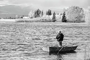 Montana Prints: Solo fisherman standing in small boat on Frenchtown Lake, Montana
