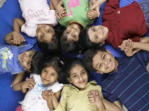 Students Prints: South Asian Indian boys and girls lay down on floor and holding hands in nursery school MR