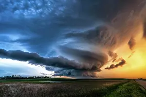 Spinning mesocyclone tornado warned storm over rural gravel road and field at sunset in Saskatechewan Canada