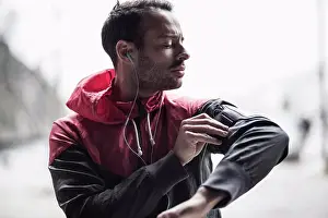 Midadult Men Prints: Sporty man adjusting arm band while listening to music
