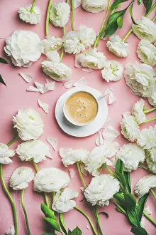 Pink Prints: Spring morning concept. Flat-lay of cup of coffee surrounded with white ranunculus flowers over light pink background