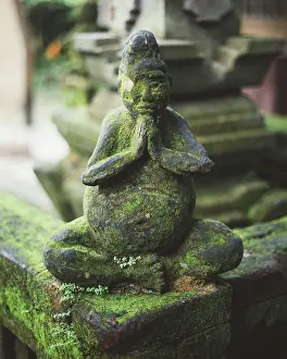 Tropical Prints: Stone fence with statue of praying monk covered with moss, Bali