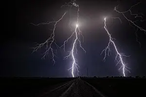 Shannon Prints: Storm with close range cloud to ground lightning flashing over old rural road in Kansas United States