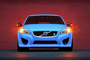 Hood Prints: Straight on static nose view of a blue 2013 Volvo C30 T5 Polestar parked next to an orange wall