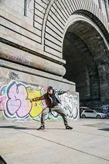 Expressive Prints: Street dancer poses wide near colorful graffiti and stone arch