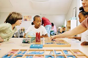 Communications Prints: Students learning spellings at table by teacher in classroom