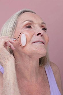 Serene People Prints: Studio shot of senior woman using face roller