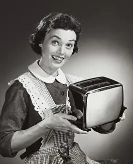 Apron Prints: Studio shot of woman holding toaster