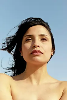 Contemplative Prints: Sunlit portrait of a woman gazing into the distance against a clear sky