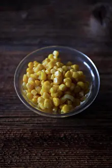 Sweet corn in a little glass bowl on a rustic wooden table