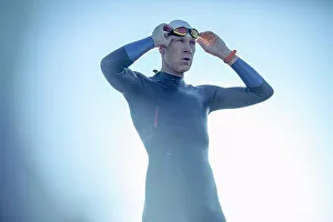 Adjusting Prints: A swimmer in a wetsuit and swimming hat, adjusting his swimming goggles