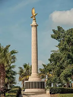 Good Weather Prints: A tall monument with a golden eagle surrounded by palm trees under a blue sky