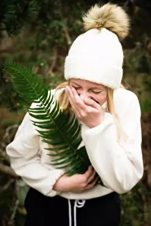 People In Nature Prints: Teen Girl in Winter Hat Holding Green Fern While Laughing