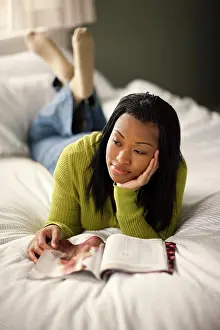20 To 25 Years Prints: Teenage girl lying on her bed day dream while reading a magazine