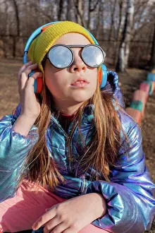 Round Prints: Teenage girl sits outdoors and listens music on headphones