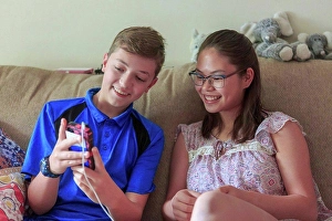 Teddy Bear Prints: Teenage girl who has Learning Disability looking at phone with her brother