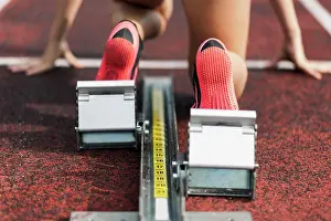 Runner Prints: Teenage runner kneeling on starting block, close up