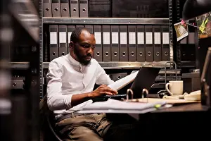 Analysis Prints: Tired cop sitting at desk surrounded by case files