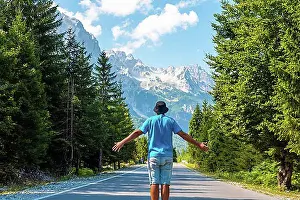 Hike Prints: A tourist in summer walking on the road in the Valbona valley