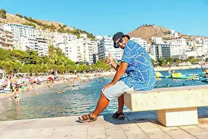 Urban Environment Prints: Tourist on vacation sitting by the sea at Saranda Beach on the Albanian Riviera in Sarande