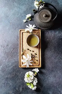 Back Ground Prints: Traditional ceramic cup of hot green tea on wooden board with black iron teapot