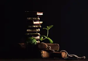 Board Prints: Triple layaered chocolate pieces stack or tower with banch of fresh mint on black background
