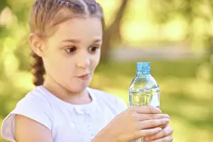 Unschuld Prints: Überrascht kaukasischen weiblichen Kind hält Wasserflasche außerhalb in sonnigen Park Surprised caucasian female child