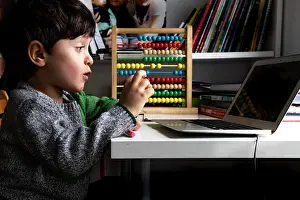 Lockdown Prints: UK, Boy looking at laptop at home