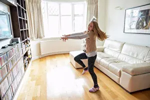 Blond Hair Prints: UK, Surrey, Girl dancing in front of TV set in living room