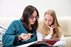 Blond Hair Prints: UK, Surrey, Mother assisting daughter doing homework at home
