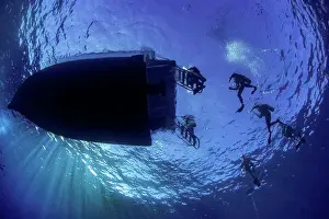 Medium Group Prints: Underside view of a dive boat and divers entering the water at Molokini dive site; Hawaii
