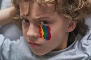 Depressed Prints: Unhappy boy with rainbow under eye looking at camera at home during quarantine