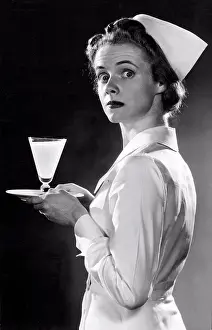 Unitedstates Prints: United States: c. 1947 A nurse looking surprised as she is photographed carrying a glass of milk on a tray