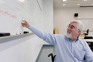 Business And Occupation Prints: University professor with Muscular Dystrophy writing on a whiteboard in a classroom