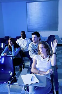 Hand Raised Prints: University students attending lecture while one student with hand raised in the classroom