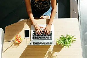Anonymous Prints: From above unrecognizable lady typing on laptop keyboard while sitting at table with healthy fruit salad