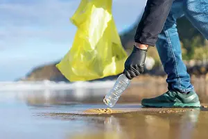 Coast Prints: Unrecognizable person collecting garbage or plastic on the beach. ecology concept