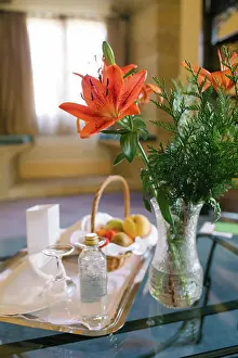 Mothers Day Prints: Vase with beautiful flowers and tray with breakfast food placed on glass table in luxury hotel room in morning