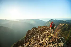 Beginnings Prints: Side view of backpacker approaching mountain summit at sunset