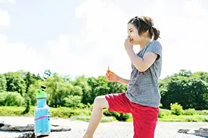 People In Nature Prints: Side view of a child eating a snack on the beach