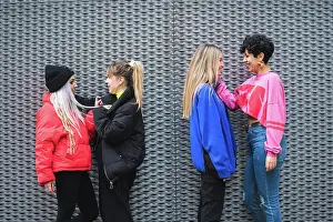 Conversation Prints: Side view of diverse couples of lesbians in stylish colorful wear standing in front of each other smiling
