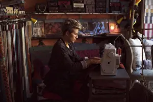 Worked Prints: Side view of female fashion designer using sewing machine in studio