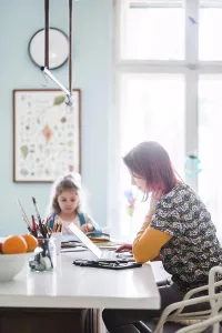 Communications Prints: Side view of mid adult women working on laptop while sitting with girl at kitchen island