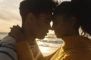Valentine Prints: Side view of multiracial couple romancing while hugging each other at beach during sunset