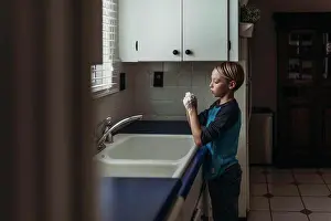 Flooring Prints: Side view of school aged boy wasking hands at sink in kitchen