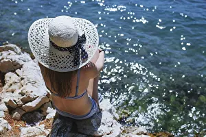 Bikini Prints: Back view of a woman with hat sitting by the sea