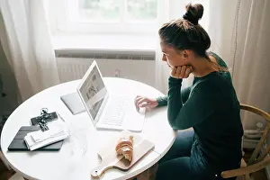 Communications Prints: Side view of woman reading food recipe on laptop at table in living room