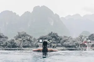 Hills Prints: Back view of woman in swimming pool looking at mountains in rainy day
