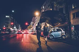Straight Prints: Back view of young couple with black flag walking on the street by night