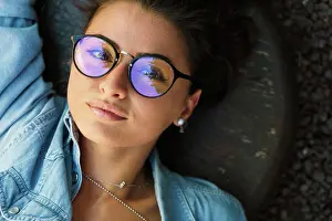 Smart Prints: Top view of young stylish girl wearing elegant eyeglasses and looking at camera while lying on ground